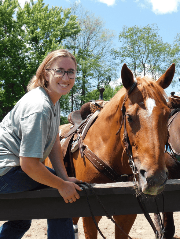 Woman sitting on a fence with horse