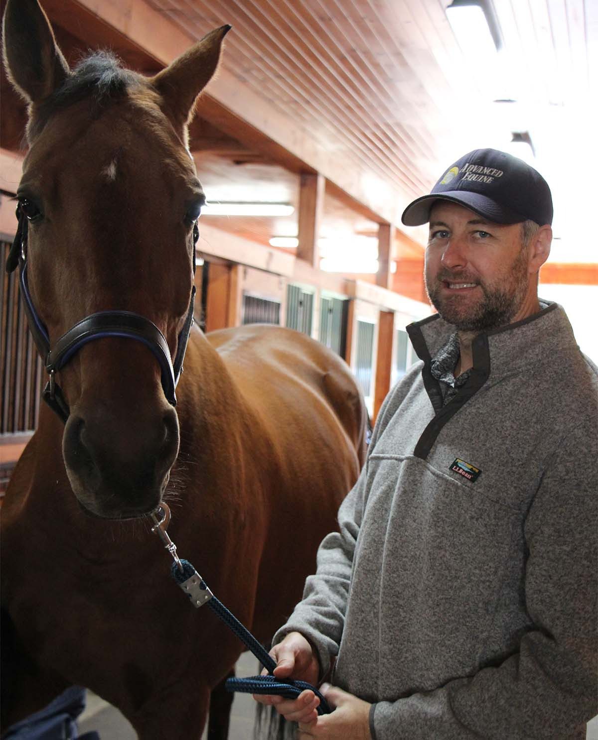 Smiling man beside brown horse