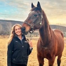 Woman smiling with horse in field