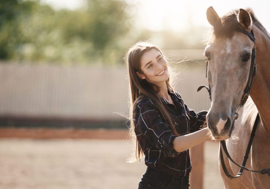 Woman smiling next to horse outdoors